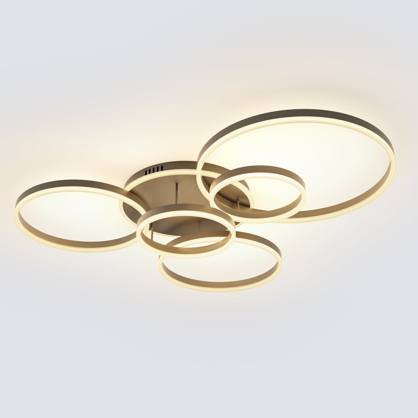 Modern ceiling light fixture with interlocking circular rings in a brushed gold finish, emitting a warm white glow against a plain light gray background.