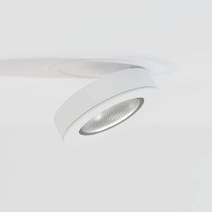 White adjustable downlight with ribbed reflector mounted on ceiling against white background.
