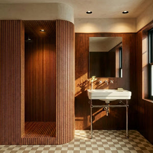 Recessed downlight with black finish installed in luxury bathroom ceiling above wooden shower enclosure and vanity.