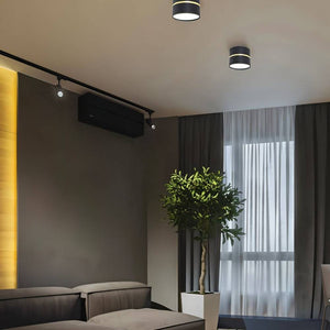 Black and gold ceiling downlights installed in a modern bedroom with dark walls and floor-to-ceiling curtains.