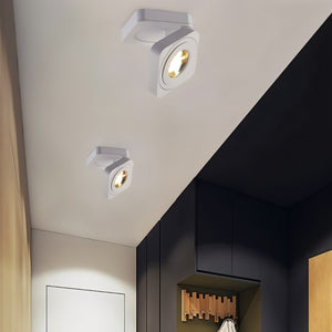 White adjustable square downlights with warm LED glow mounted on ceiling above modern entryway with dark cabinetry.