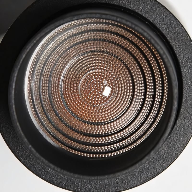 Recessed downlight with concentric copper mesh reflector and black trim ring on white background.
