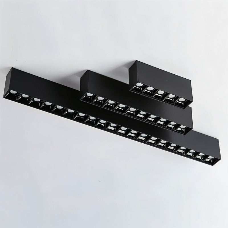 Black modular ceiling downlight fixtures with multiple recessed LED units mounted on white wall.