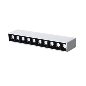 Long rectangular recessed downlight fixture with white top and black front panel containing nine circular light openings.
