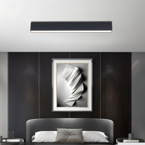 Black linear downlight fixture mounted on white ceiling above modern bedroom with dark wall paneling.