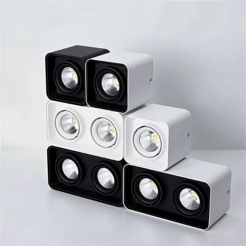 Modular LED downlights in black and white finishes stacked in a pyramid arrangement on a neutral background.