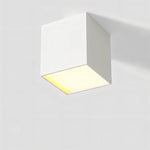 White square ceiling downlight with warm LED glow on neutral background.