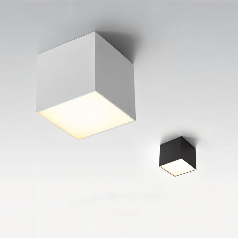 Two modern cube ceiling downlights in white and black finishes mounted on a gray wall with warm illumination.