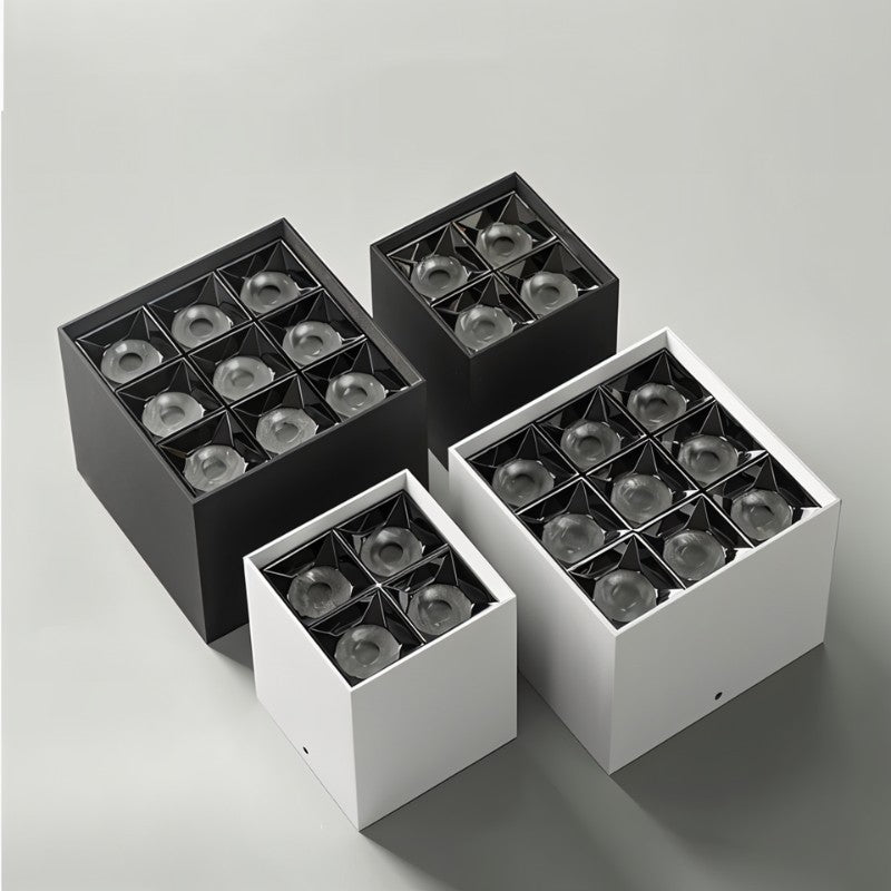 Four square recessed downlight fixtures in black and white finishes displayed on a neutral gray background.