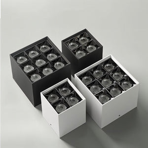 Four square recessed downlight fixtures in black and white finishes displayed on a neutral gray background.