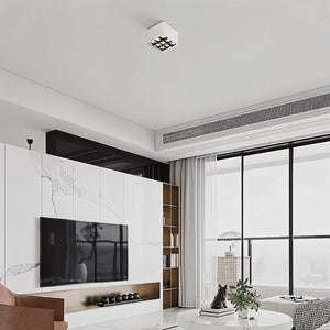 Square recessed ceiling light with geometric metal shade in white finish, installed in modern living room with marble walls.
