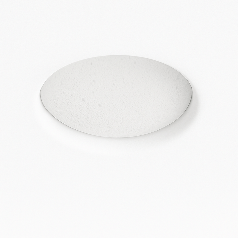 Illuminated circular wall light with warm glow, textured surface, mounted on white wall above gray sofa in modern interior se